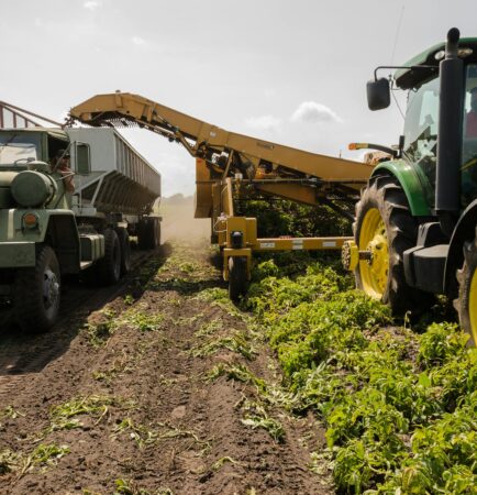 Caminhão e colheitadeira trabalhando em plantação