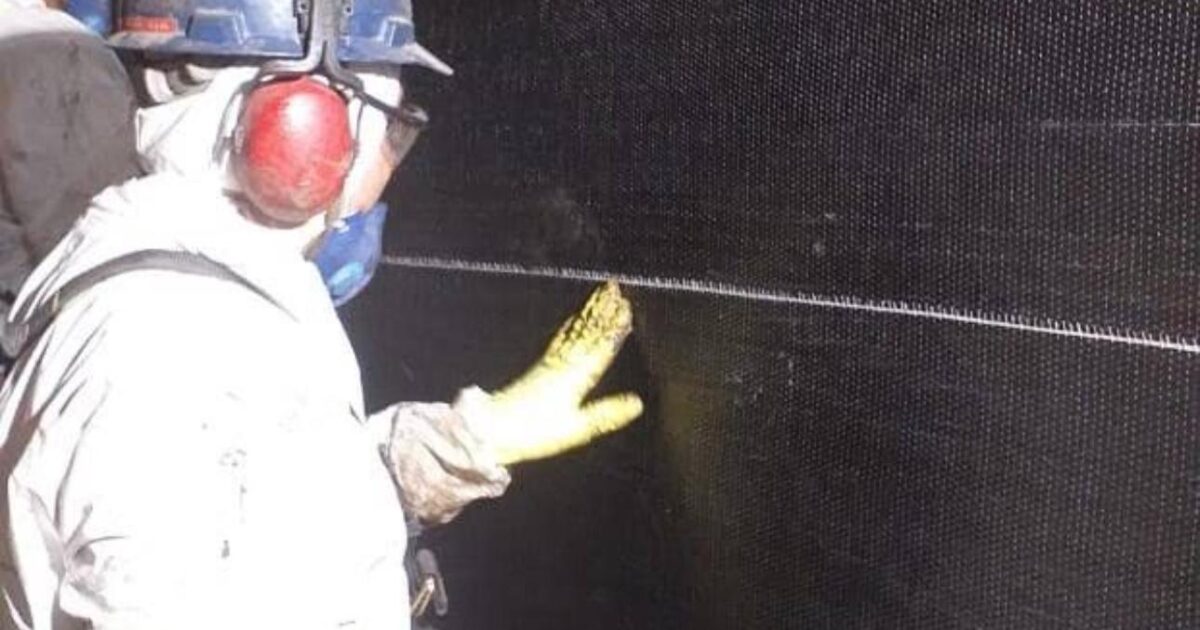 Trabalhador aplica placas de fibra de carbono em estrutura de concreto