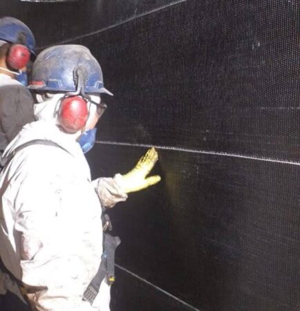 Trabalhador aplica placas de fibra de carbono em estrutura de concreto